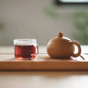 clay teapot with clear mug of dark tea